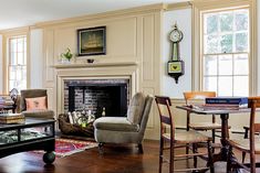 a living room filled with furniture and a fire place in front of a clock mounted on the wall