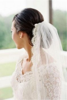 a woman in a wedding dress looking out the window with a veil on her head