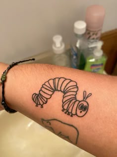 a person with a tattoo on their arm that has a drawing of a caterpillar