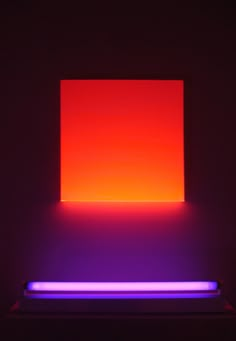 an illuminated square in the middle of a room with purple and red lights on it