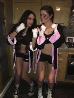 two women standing next to each other in the kitchen wearing boxing gloves and holding their fists up