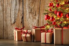 three wrapped presents sitting in front of a christmas tree with red and gold ornaments on it