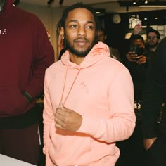 a man in a pink hoodie standing next to a table