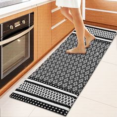 a woman standing on a kitchen rug in front of an oven