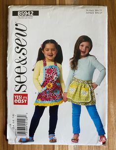 This See & Sew kid's apron pattern #B5942 is an uncut kid's apron pattern for sizes 3-4, 5-6, or 7-8. The 'easy sewing' kid's aprons comes with 2 options but eliminating the overskirt on View A increases it to 3. These aprons leave lots of room for fun fabrics and embellishments. A finished apron makes a fun yet inexpensive child's birthday gift. Make a half dozen aprons and donate to your child's classroom! Girls Sewing Patterns, Child Apron Pattern, Sewing Templates, Craft Apron, Girl Apron, Apron Sewing Pattern, Simplicity Dress, Childrens Aprons, Sewing Aprons