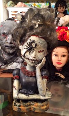 two creepy dolls sitting next to each other in front of a shelf with skulls on it