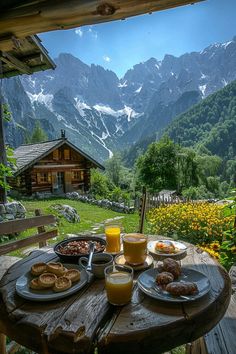 a wooden table topped with breakfast foods on top of a lush green forest covered hillside