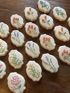 twelve decorated cookies with flowers on them sitting on a table next to eachother