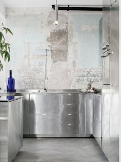 an industrial kitchen with stainless steel cabinets and counter tops, along with a blue vase