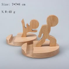 two wooden figurines are standing on small bases, one is holding the other's hand