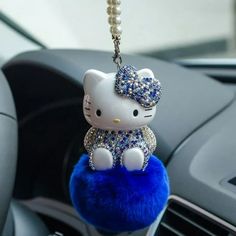 a hello kitty keychain hanging from the dashboard of a car with blue fur