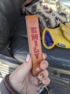 a person holding a leather keychain with the word family written on it