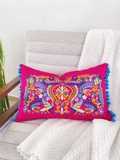 a pink pillow on a white chair next to a potted plant