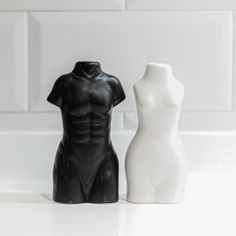 two black and white ceramic mannequins sitting next to each other on a counter