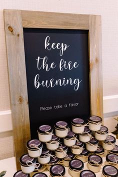 a sign that says keep the fire burning on top of a table filled with tea cups