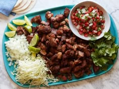 a blue plate topped with meat and veggies next to a bowl of salsa