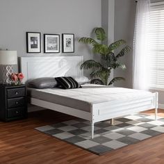 a white bed sitting on top of a wooden floor next to a black and white checkered rug