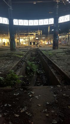 an abandoned train station with the lights on and broken down tracks in the foreground