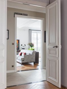 an open door leading to a living room with white walls and wood flooring on the other side