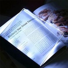 an open book sitting on top of a table next to a light up box with the pages lit up