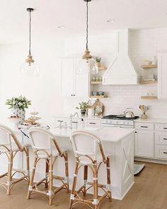 a kitchen with white cabinets and stools next to an island in the middle of the room