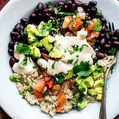 a white plate topped with black beans, rice and veggies next to a fork