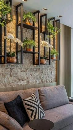 a living room filled with furniture and lots of plants on the wall above it's windows