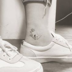 a small tattoo on the ankle of a woman's foot, with two birds sitting on