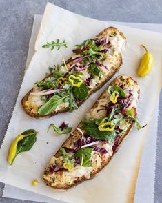 two slices of bread topped with veggies on top of a piece of parchment paper