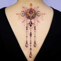 the back of a woman's neck is adorned with colorful jewels and an intricate design