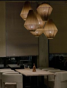 a dining room table with chairs and lights hanging from the ceiling