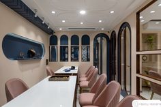 a long table with pink chairs in front of it and some blue windows behind it