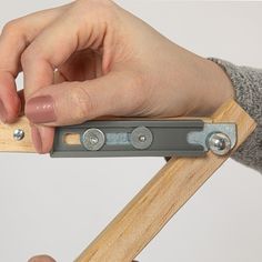 a person is holding a piece of wood with two metal clips attached to the handle