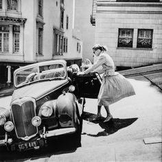 a woman pushing a car down the street