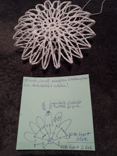 a piece of paper with writing on it next to a string art doily ornament