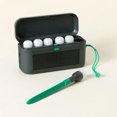 an electronic device with four white balls in it and a green pen next to it