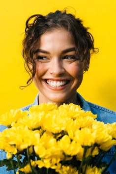 a smiling woman holding yellow flowers in front of her face by luma studio for stocks