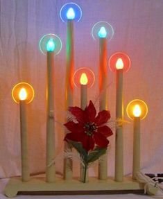 a lighted candle holder with six candles and a poinsettia in the center