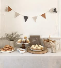 a table topped with cakes and cupcakes next to a bunting banner