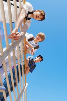 three young people standing on top of a wooden structure with blue sky in the background