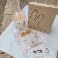 a paper bag sitting on top of a table next to a drink and donut