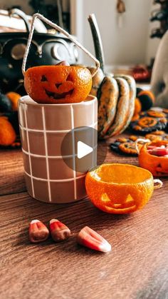 an orange sitting on top of a wooden table next to other pumpkins and candies