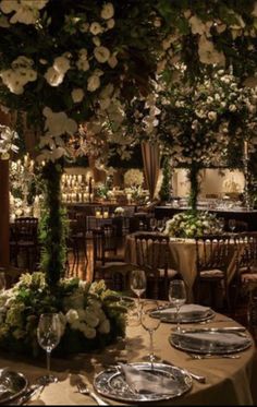 the tables are set with silverware and white flowers on them, along with greenery