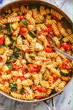 a pan filled with pasta and vegetables on top of a table