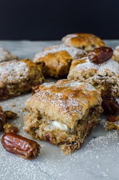 several pieces of dessert sitting on top of a table covered in powdered sugar and raisins