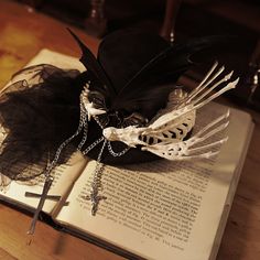 an open book sitting on top of a wooden table next to a feathered hat