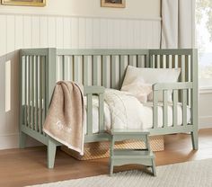 a baby crib with a blanket on top of it next to a chair and rug