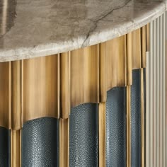 a marble topped table sitting in front of a wall with gold and black lines on it