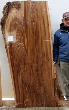 a man standing next to a large piece of wood