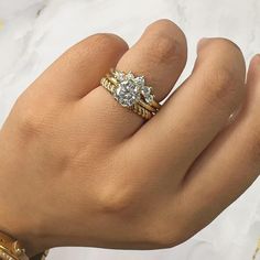 a woman's hand with two gold rings on it and a diamond ring in the middle